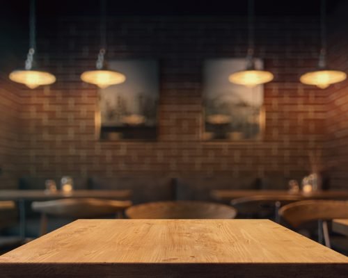 Empty tabletop in the coffe shop at night over defocused background with copy space