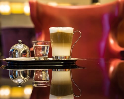 Glass of latte Coffee cup and syrup on the table in lounge bar background.